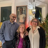 Julie Wilson, center, the wife of late artist John Wilson, and their children Roy and Erica pose with one of John's self portraits. Photo by Maddie Browning